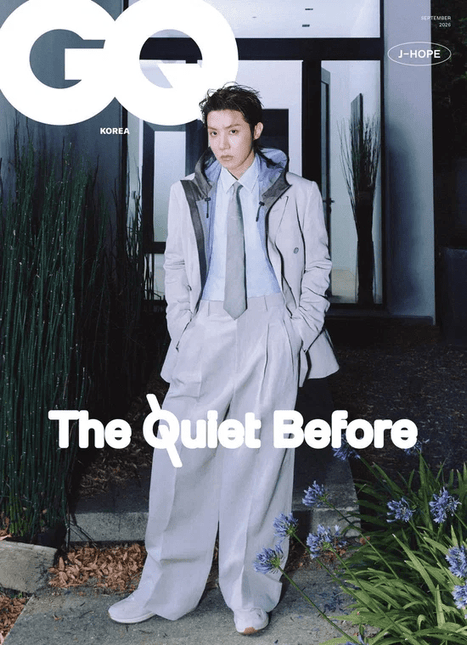 BTS j-hope GQ Korea September 2026 Cover A — oversized ash-grey and cream suit with a slim tie, standing on an outdoor garden path, 'The Quiet Before' logo in white, minimalist neutral-tone photoshoot.